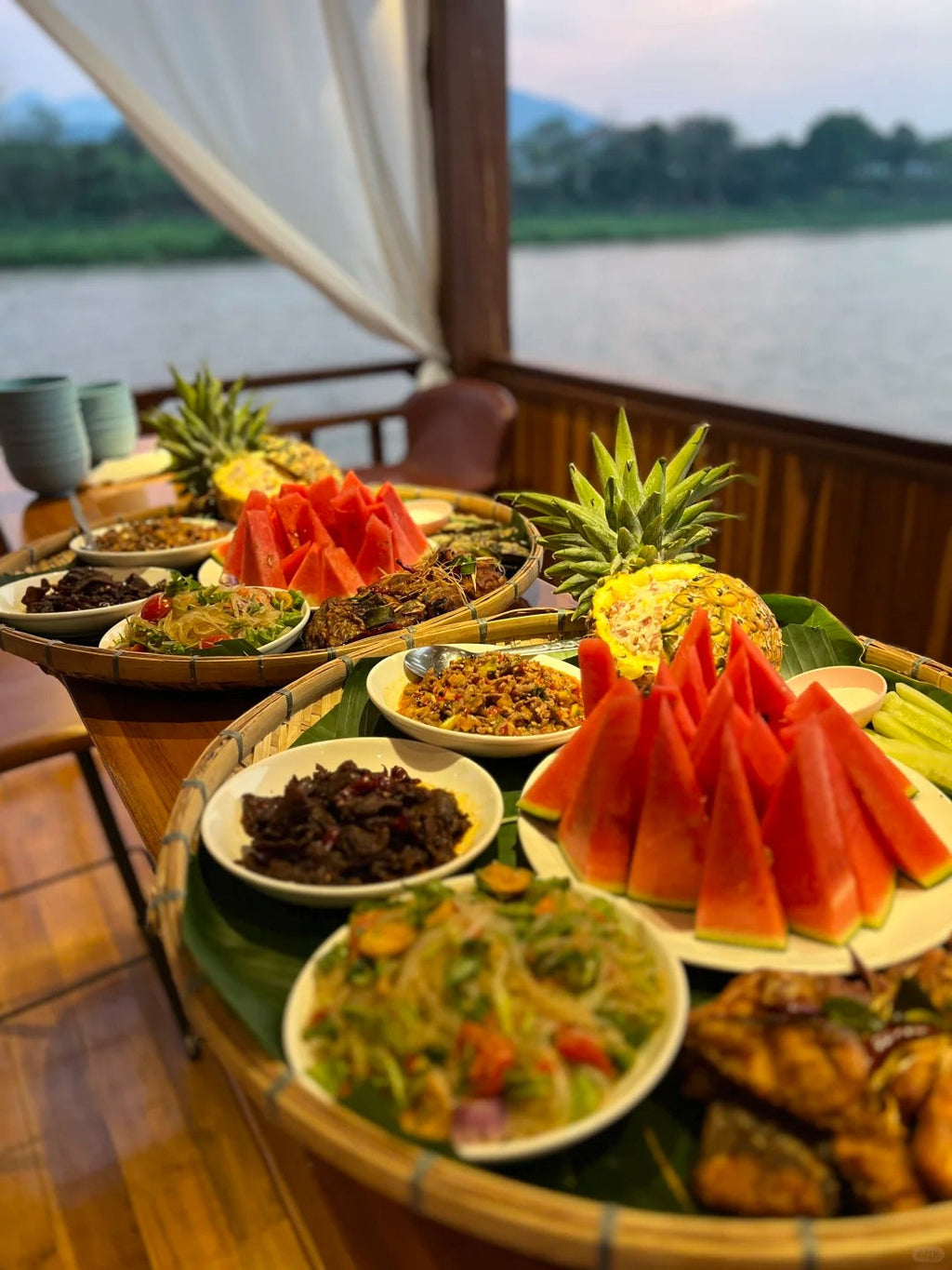 Diverse array of fruits and dishes on a boat with a scenic background