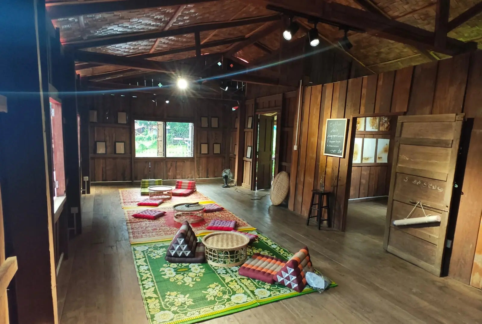 Traditional room with wooden walls and floor, featuring decorative rugs and furniture. Xiangman Old House Café · Hiking Station