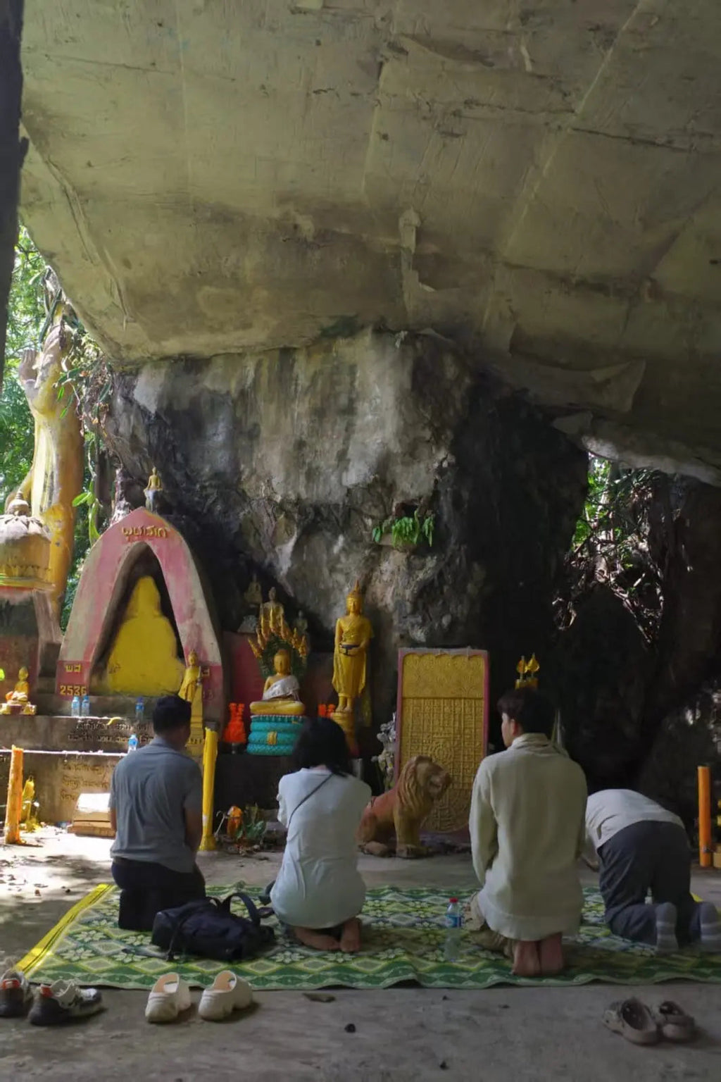 praying in a cave with religious statues and offerings.